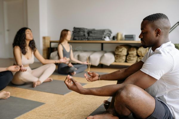 A diverse group practicing mindfulness meditation with incense in a serene indoor setting.